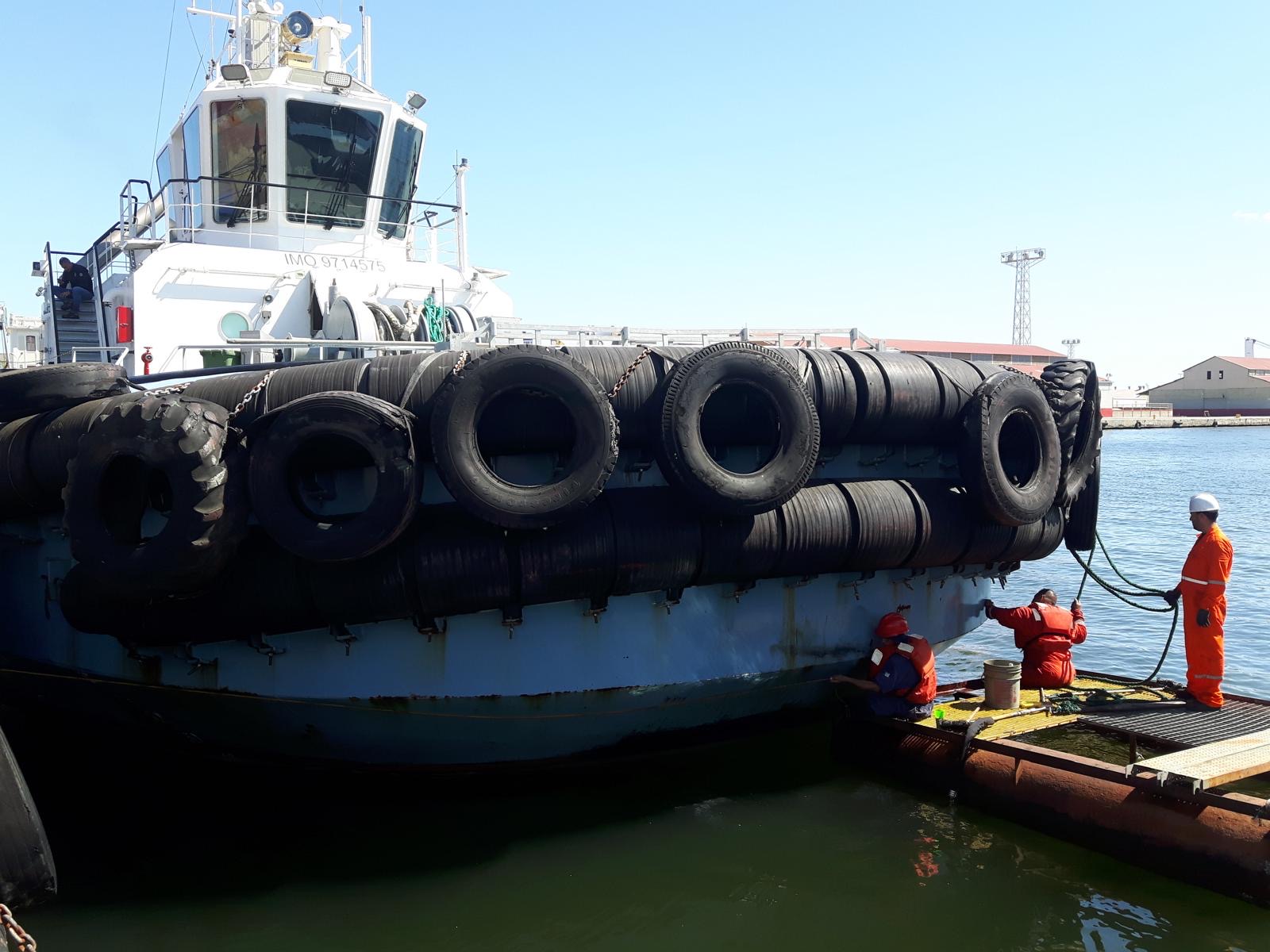 Hull inspection of a tug at the waterline from a work float